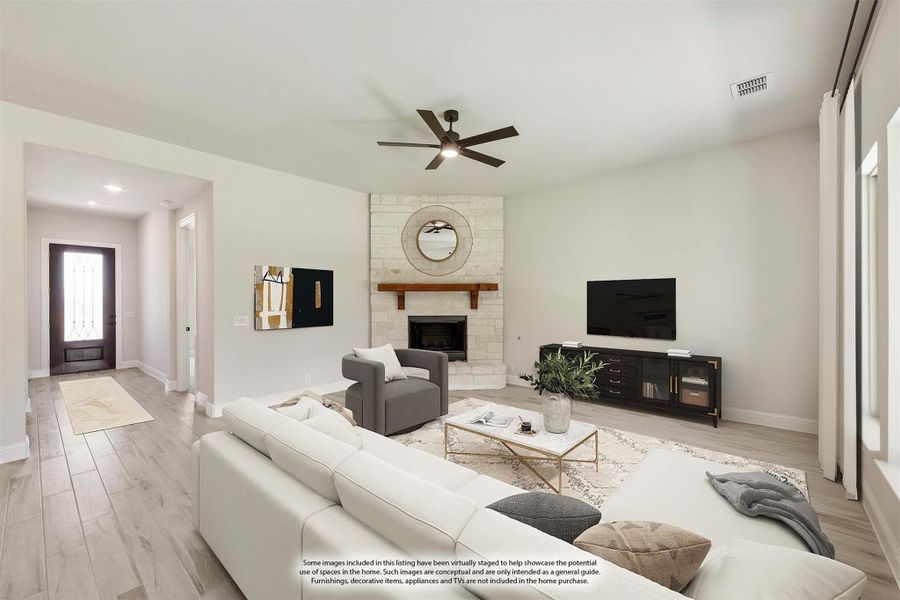 Living room with stone fireplace, ceiling fan, light wood floors, and white sectional sofa