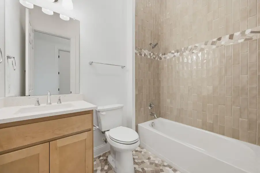 Bathroom featuring shower / bathtub combination, vanity, and light tile patterned floors