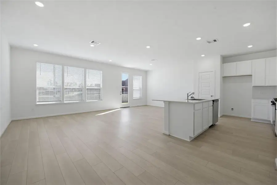 Flooded with natural light from large windows and a patio door, the Great Room feels bright and airy. Recessed lighting adds to the welcoming atmosphere, perfect for gathering with family and guests.