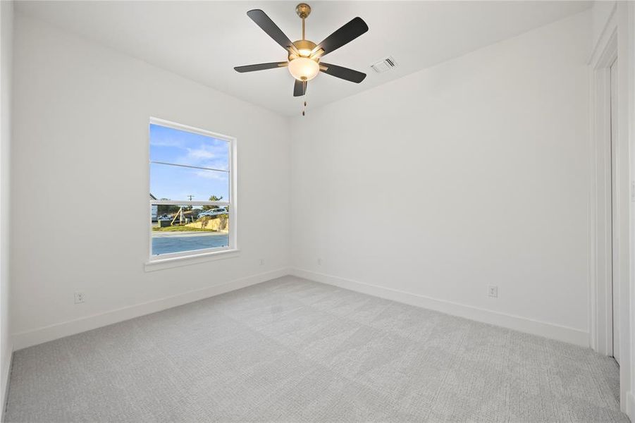 Spare room featuring light colored carpet and a ceiling fan