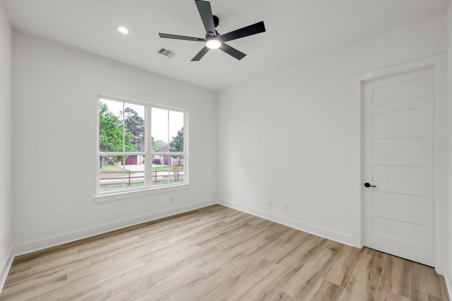 Versatile secondary room with abundant natural light and wood-look flooring, ideal for a bedroom, home office, or study. Large window overlooks the surrounding acreage.