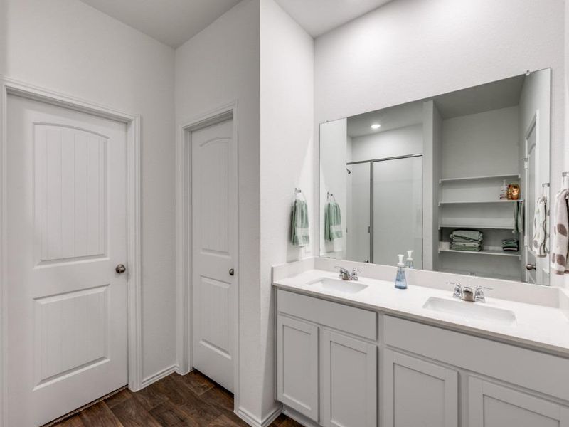 Full bath with a closet, a stall shower, double vanity, and dark wood-style floors