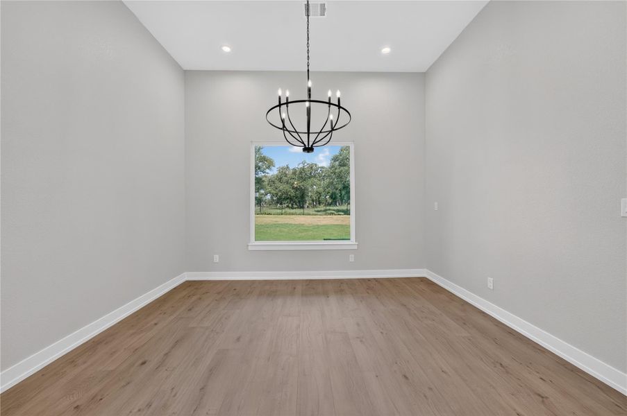 High ceilings and clean wood-style flooring anchor this versatile dining space overlooking the yard.