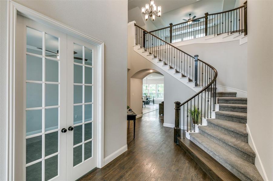 Entrance foyer featuring a two story foyer, french doors, a chandelier, and dark hardwood / wood-style flooring