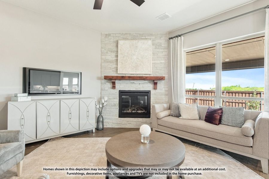 Living room with stone fireplace, wood mantel, ceiling fan, and large windows overlooking a deck