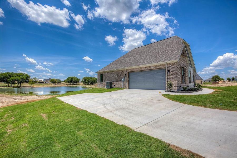 View of home's exterior with a water view, a garage, and a yard