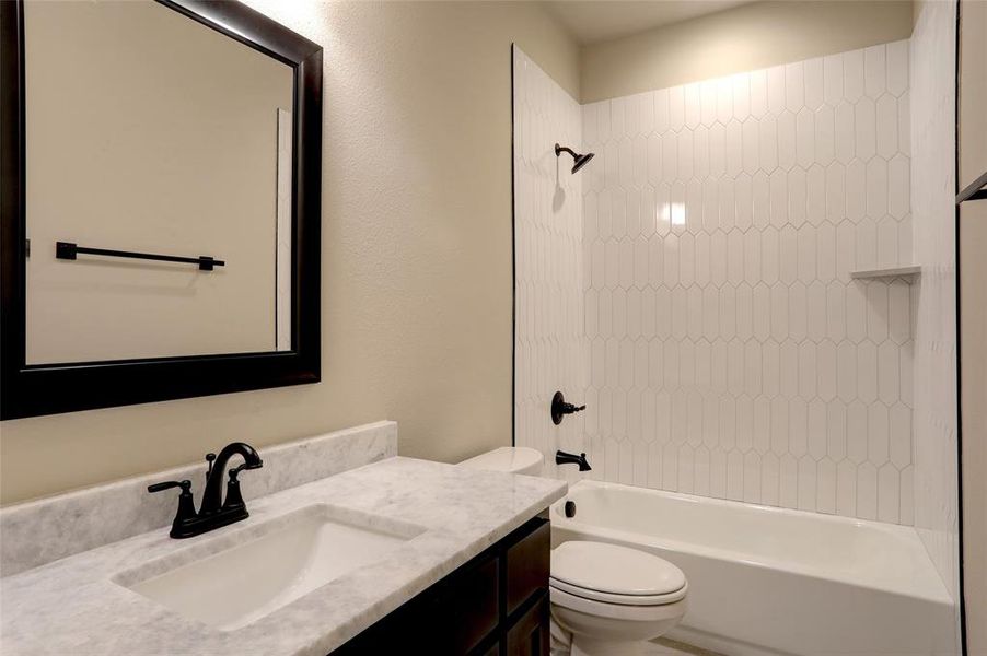 Full bathroom featuring tiled shower / bath, vanity, and toilet