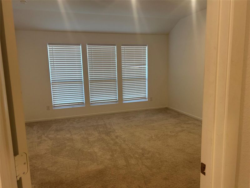 This is the view of the master bedroom and three large windows with gray carpet. This is the view of the master bedroom and three large windows with gray carpet.