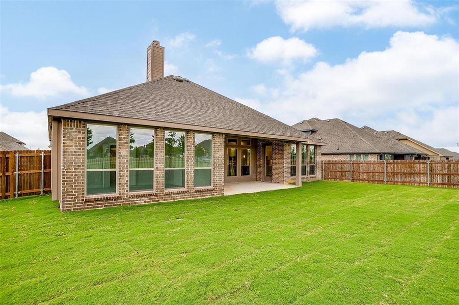 Back of property featuring a patio area and a lawn