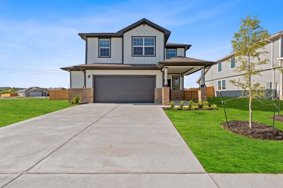 View of front facade with brick siding, board and batten siding, an attached garage, and concrete driveway View of front facade with brick siding, board and batten siding, an attached garage, and concrete driveway