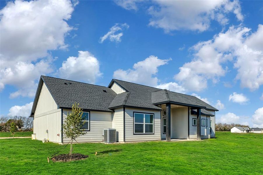 Rear view of property featuring central air condition unit and a yard