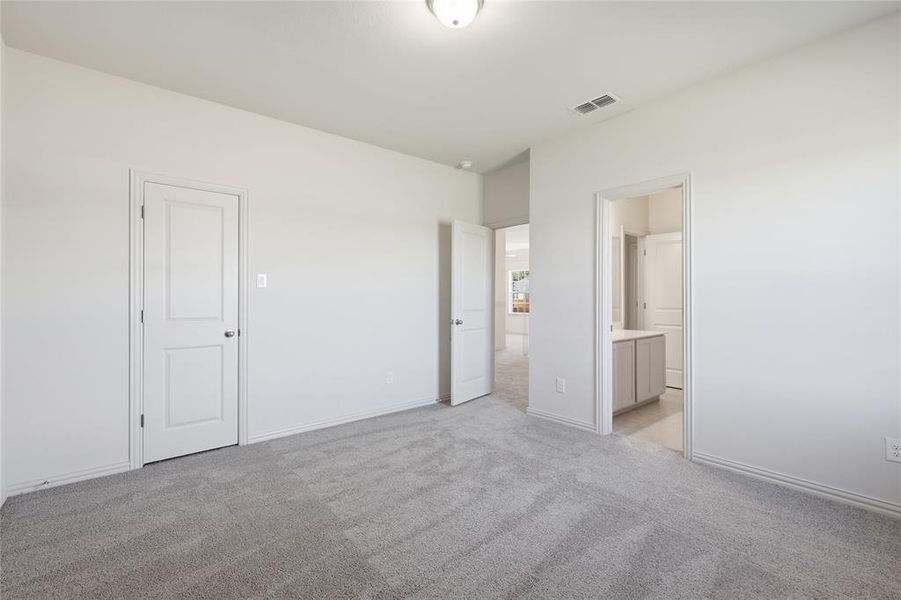 Unfurnished bedroom featuring light colored carpet and connected bathroom Unfurnished bedroom featuring light colored carpet and connected bathroom