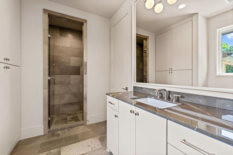 Bathroom featuring vanity, a shower stall, recessed lighting, and stone finish floors Bathroom featuring vanity, a shower stall, recessed lighting, and stone finish floors