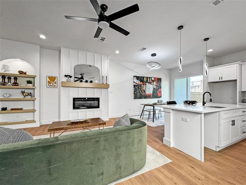 Living room with a fireplace, light wood-type flooring, ceiling fan, and recessed lighting