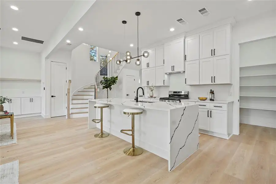 Kitchen with pendant lighting, light stone countertops, white cabinets, recessed lighting, and light wood-type flooring