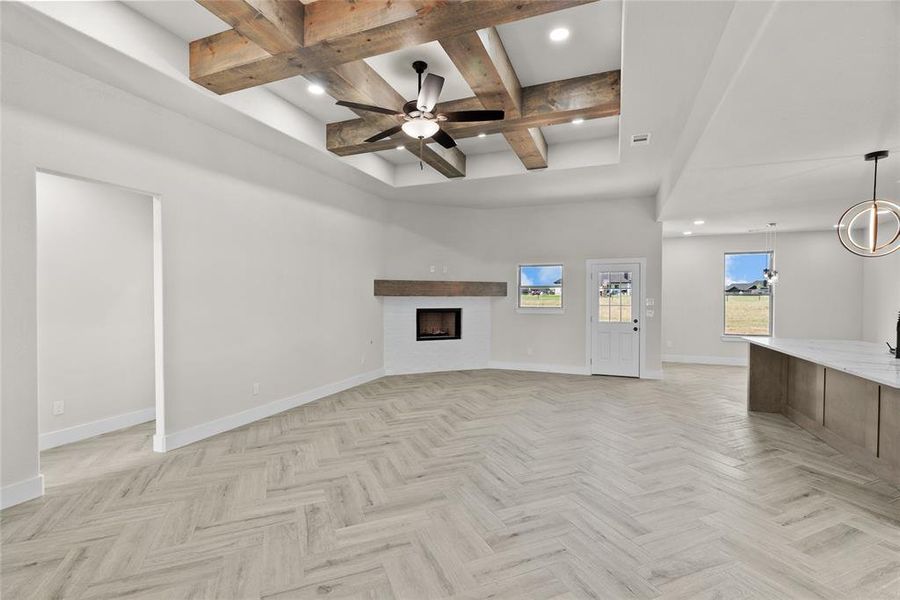 Unfurnished living room with ceiling fan, beam ceiling, and light parquet flooring