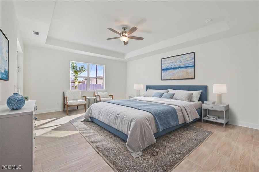Bedroom featuring a raised ceiling, wood finish floors, and ceiling fan