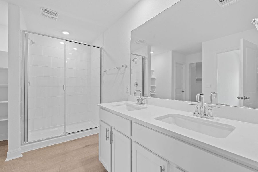 Full bath featuring double vanity, light wood-style flooring, a shower stall, recessed lighting, and a walk in closet Full bath featuring double vanity, light wood-style flooring, a shower stall, recessed lighting, and a walk in closet