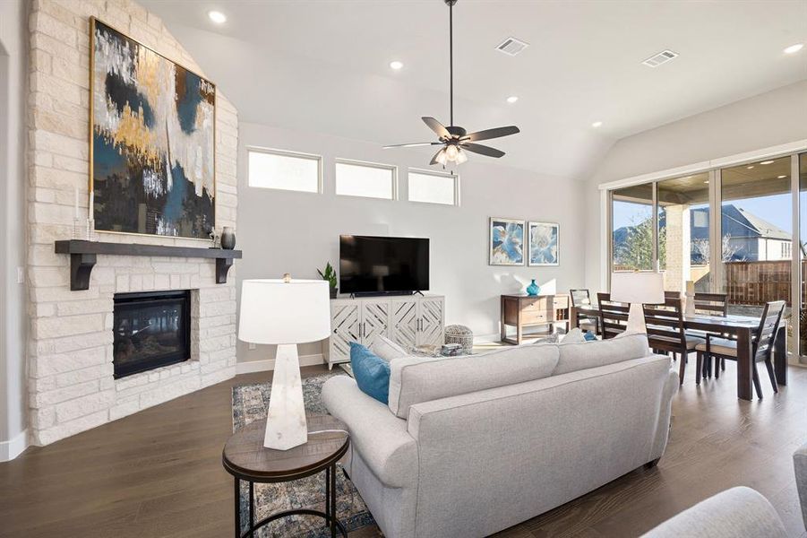 Living room featuring lofted ceiling, a stone fireplace, dark hardwood / wood-style floors, and ceiling fan