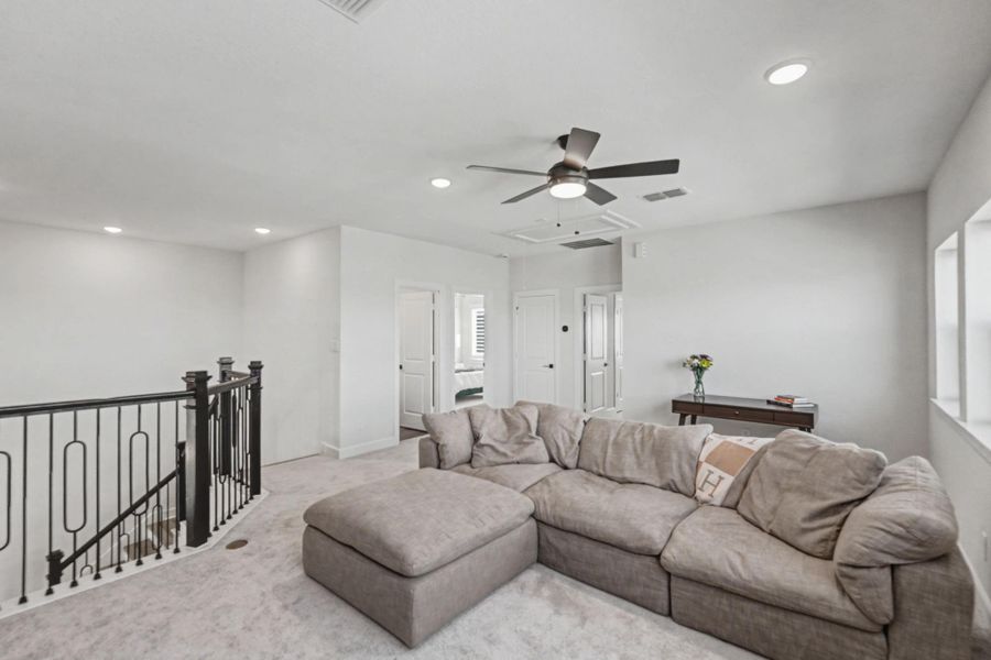 The second-floor provides a flexible secondary living area, perfect for relaxation or entertainment. Plush carpeting makes the space inviting, and multiple doors lead to bedrooms and storage.