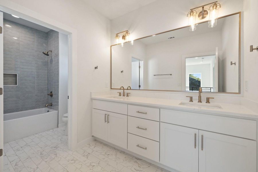 Bathroom featuring marble finish floor, a sink, toilet, and double vanity