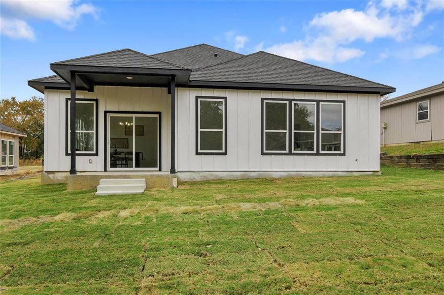 Rear view of property featuring roof with shingles and a lawn Rear view of property featuring roof with shingles and a lawn