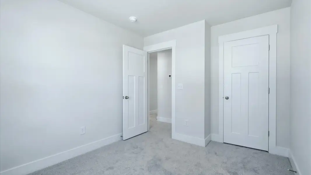 Notable secondary bedroom offering cozy carpeted flooring and a stylish walk-in closet by DRB Homes