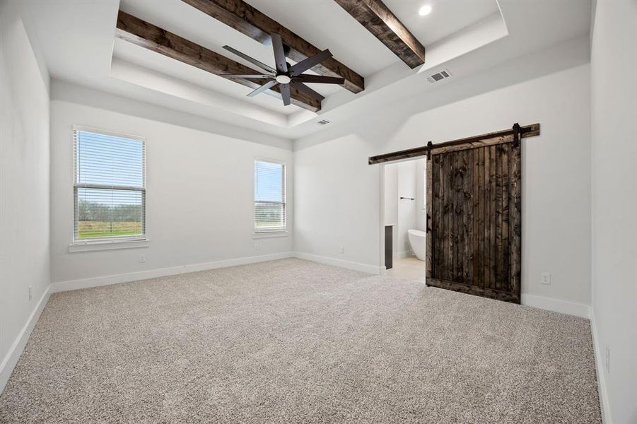 Unfurnished bedroom with visible vents, baseboards, light colored carpet, a tray ceiling, and beam ceiling