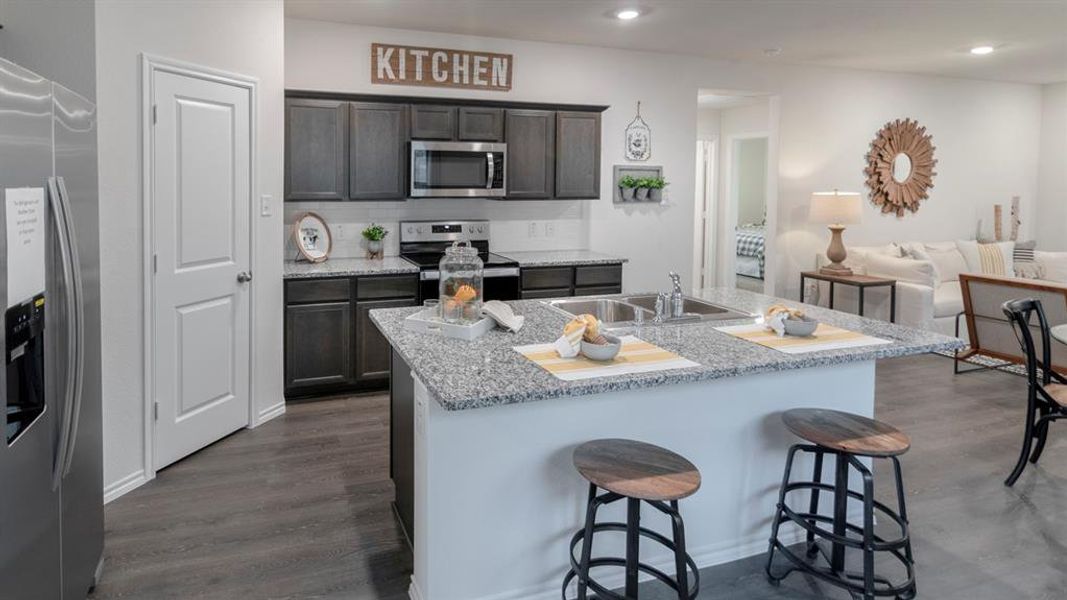 Kitchen island featuring a double-basin sink, granite countertop, and breakfast bar seating Kitchen island featuring a double-basin sink, granite countertop, and breakfast bar seating
