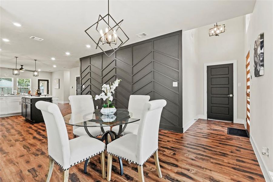 Dining space with a chandelier, dark wood-type flooring, recessed lighting, and an accent wall Dining space with a chandelier, dark wood-type flooring, recessed lighting, and an accent wall