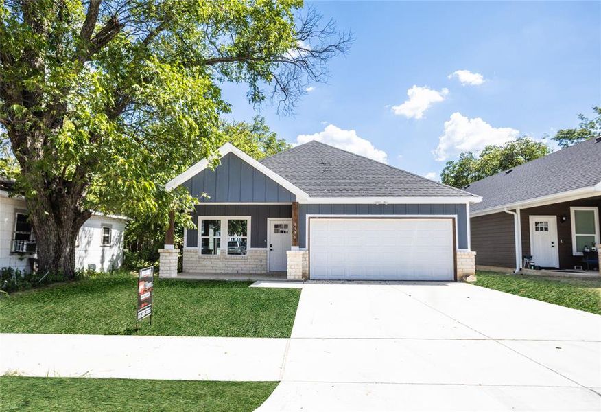 Ranch-style house with board and batten siding, driveway, roof with shingles, a garage, and a front yard