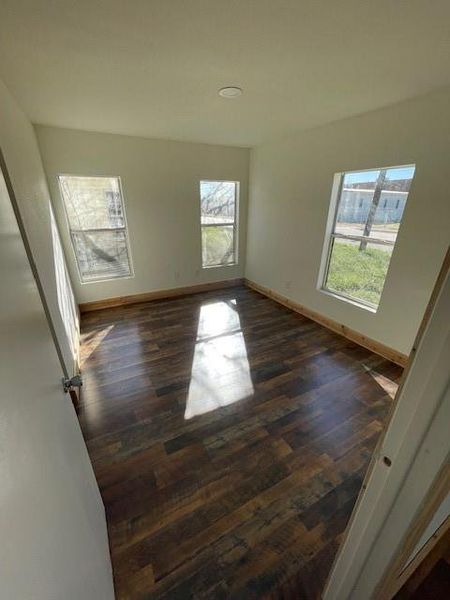 Empty room with dark wood-type flooring and baseboards