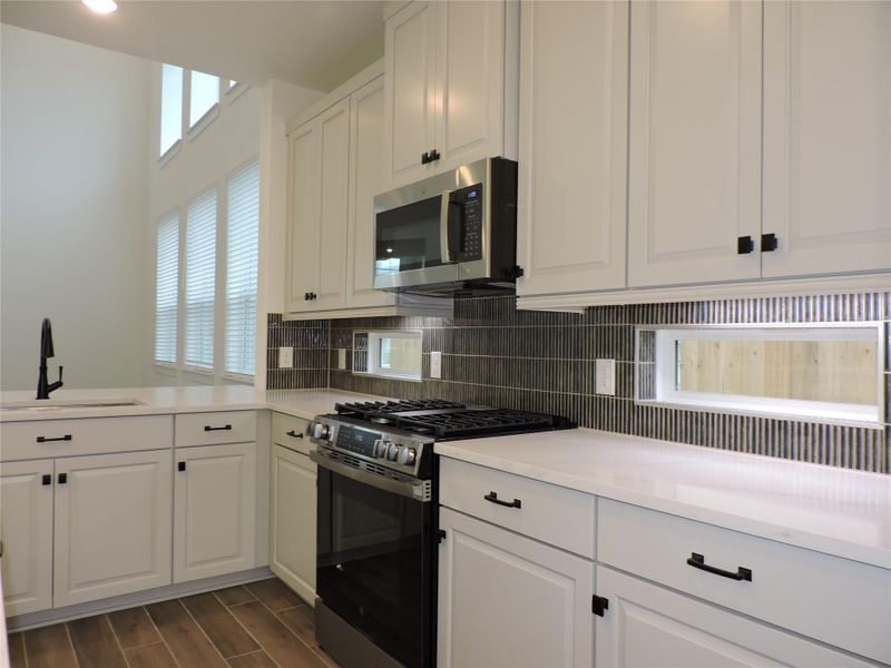 The framed windows on each side of the Gas range add detail and natural lighting.