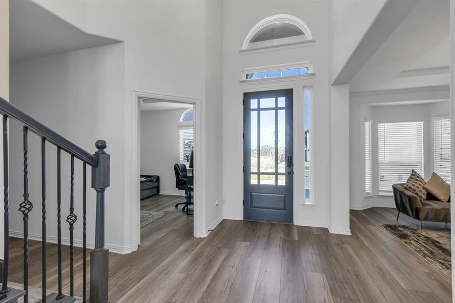 Entryway featuring a tray ceiling, hardwood / wood-style flooring, and a towering ceiling