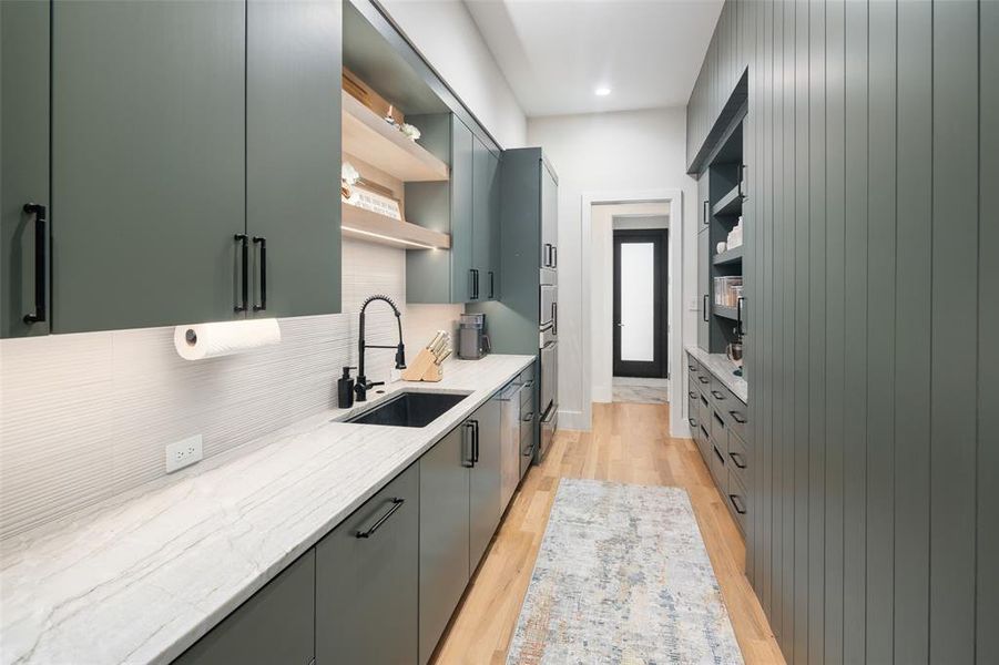 Fully equipped catering kitchen offering additional functionality with a secondary sink, dishwasher, double ovens, and an extra refrigerator. Custom cabinetry and a built-in pantry provide abundant storage, creating the perfect space for meal prep while keeping the main kitchen clean and organized during entertaining.