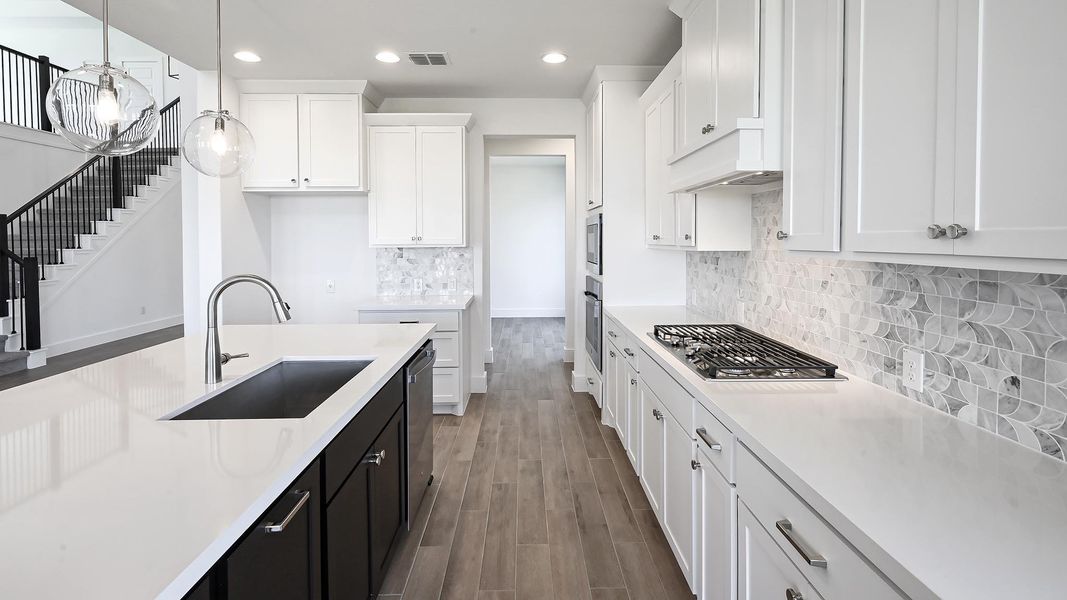 Kitchen featuring recessed lighting, wood finished floors, white cabinets, light countertops, and dark cabinets Kitchen featuring recessed lighting, wood finished floors, white cabinets, light countertops, and dark cabinets