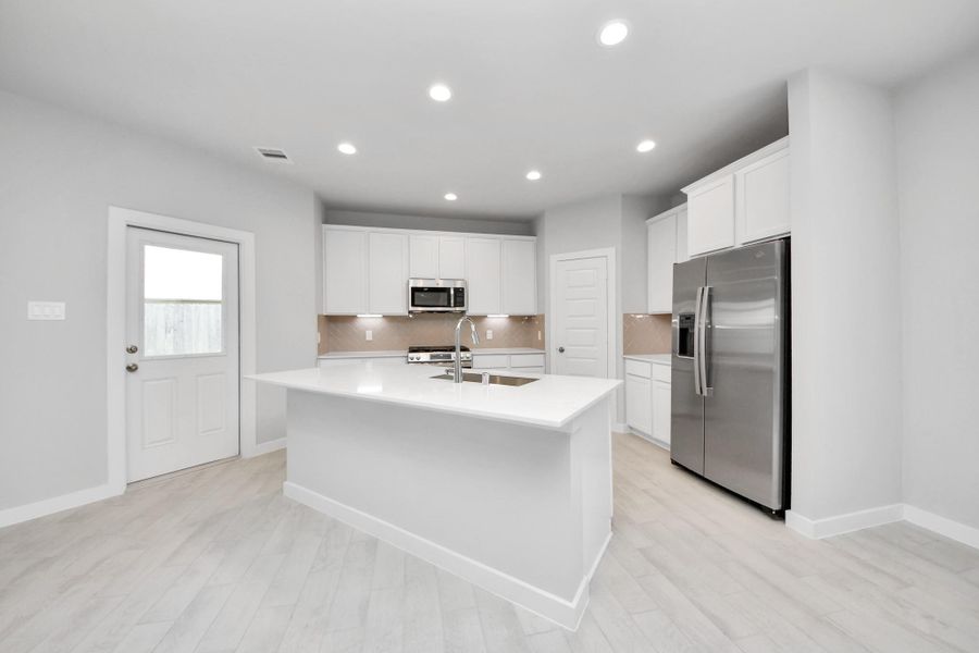 The kitchen is a culinary haven, featuring granite countertops, a tile backsplash, stainless steel appliances, 42” upper cabinets, and undercabinet lighting. Sample photo of completed home with similar floor plan. Actual colors and selections may vary. The kitchen is a culinary haven, featuring granite countertops, a tile backsplash, stainless steel appliances, 42” upper cabinets, and undercabinet lighting. Sample photo of completed home with similar floor plan. Actual colors and selections may vary.