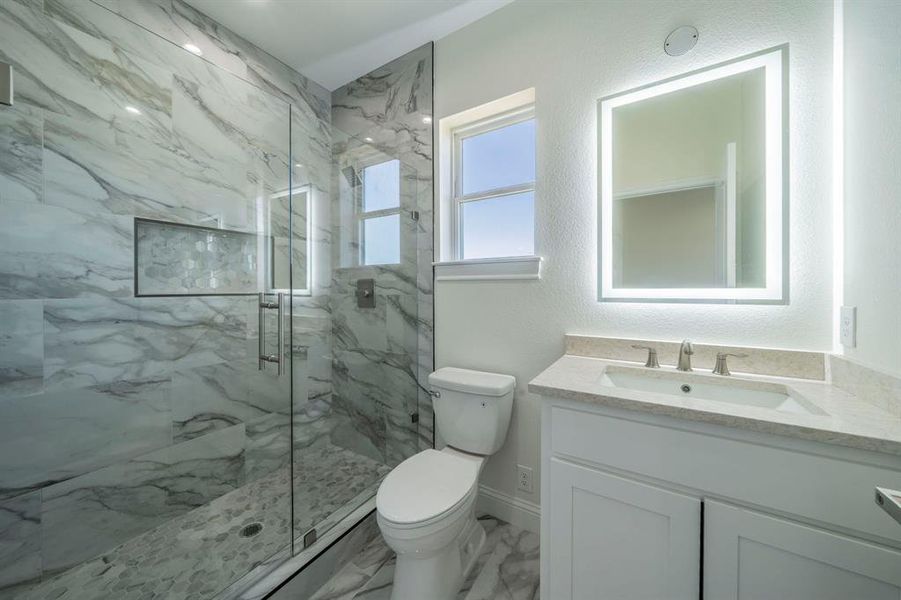 Full bathroom featuring a marble finish shower, vanity, marble look tiles, and a textured wall Full bathroom featuring a marble finish shower, vanity, marble look tiles, and a textured wall