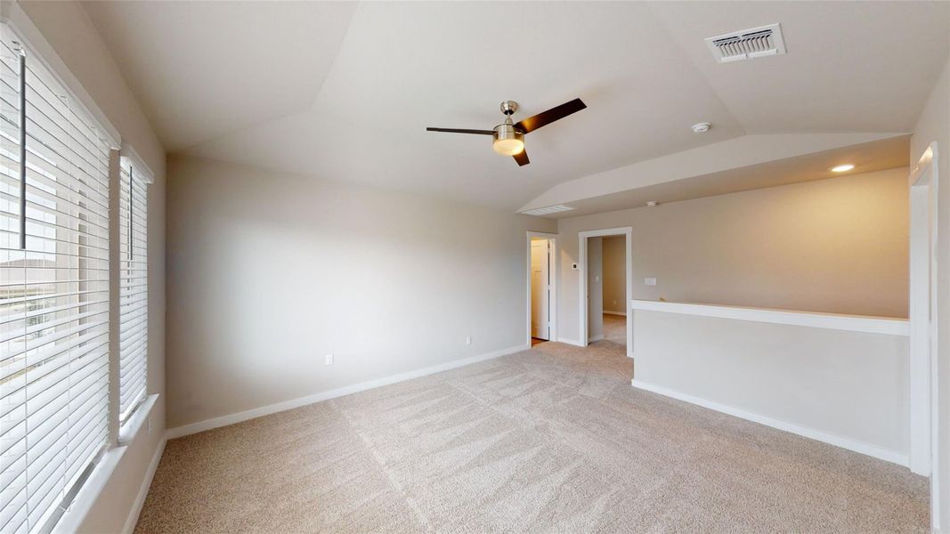 Empty room with a ceiling fan, lofted ceiling, and light colored carpet