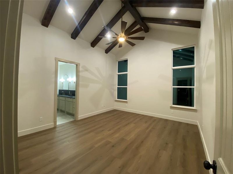 Unfurnished room featuring beamed ceiling, ceiling fan, dark hardwood / wood-style floors, and high vaulted ceiling