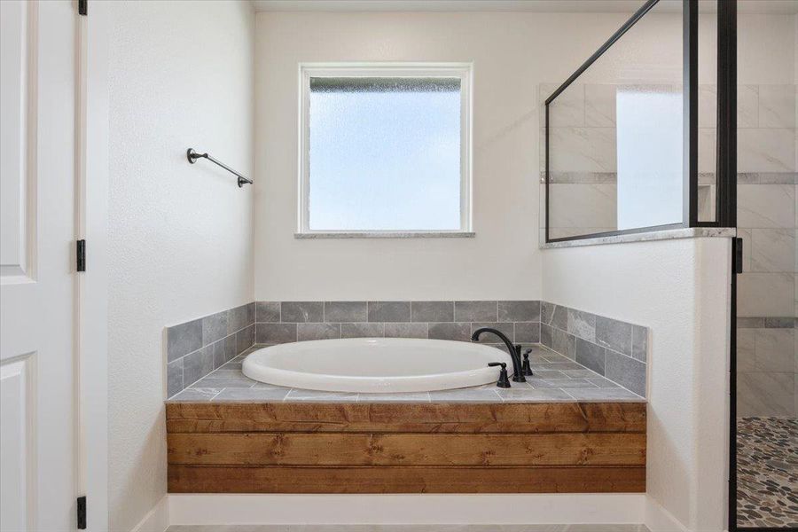 A spacious primary bathroom with a deep soaking tub and a walk-in shower invites relaxation.