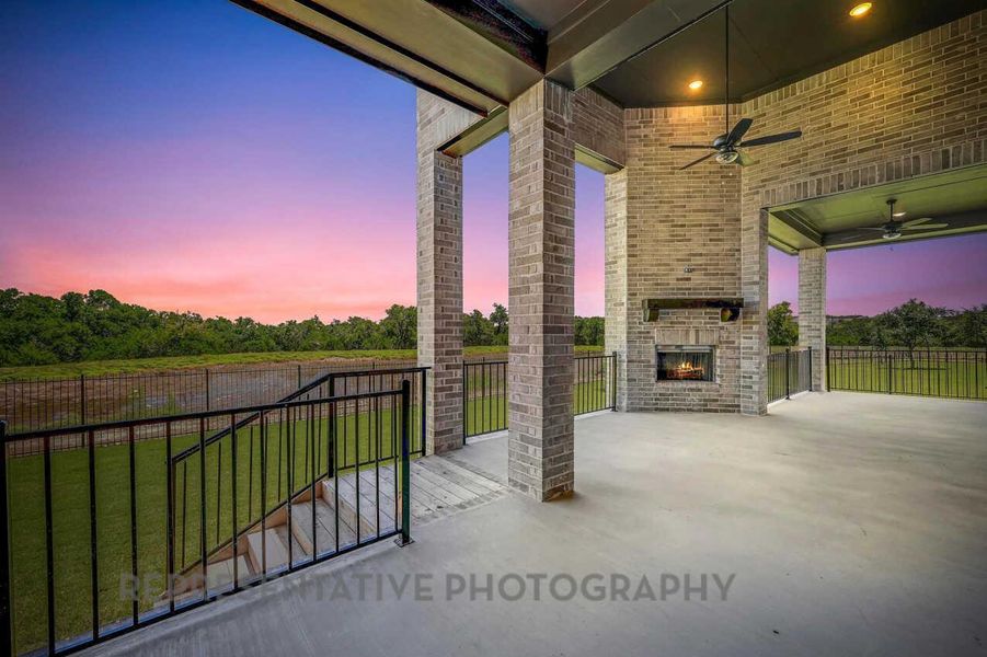 Patio terrace at dusk with an outdoor brick fireplace, ceiling fan, and a patio area Patio terrace at dusk with an outdoor brick fireplace, ceiling fan, and a patio area