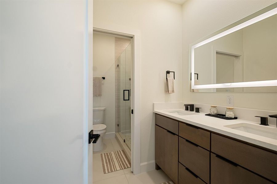 Bathroom featuring double vanity, a stall shower, and light tile patterned flooring