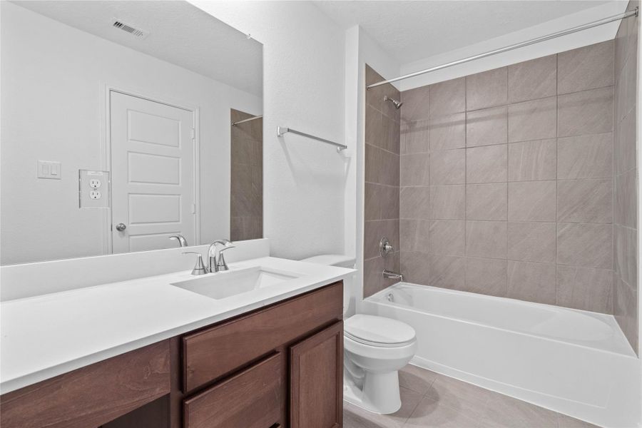 The secondary bathroom offers tile flooring, a tub/shower combination with a stylish tile surround, rich stained wood cabinetry with added knee space and elegant light countertops, a mirror, and sleek fixtures with modern finishes. The secondary bathroom offers tile flooring, a tub/shower combination with a stylish tile surround, rich stained wood cabinetry with added knee space and elegant light countertops, a mirror, and sleek fixtures with modern finishes.