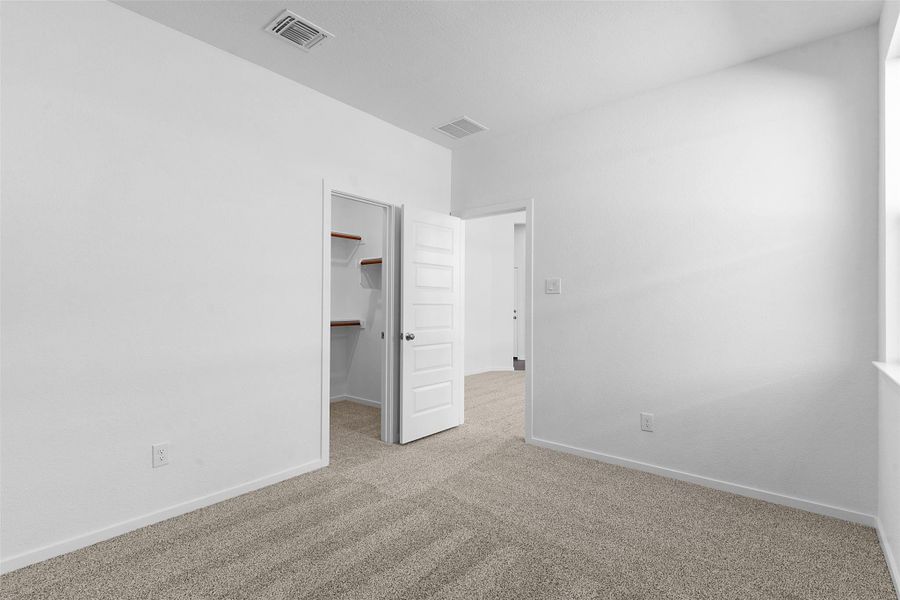 Unfurnished bedroom featuring a walk in closet and light carpet