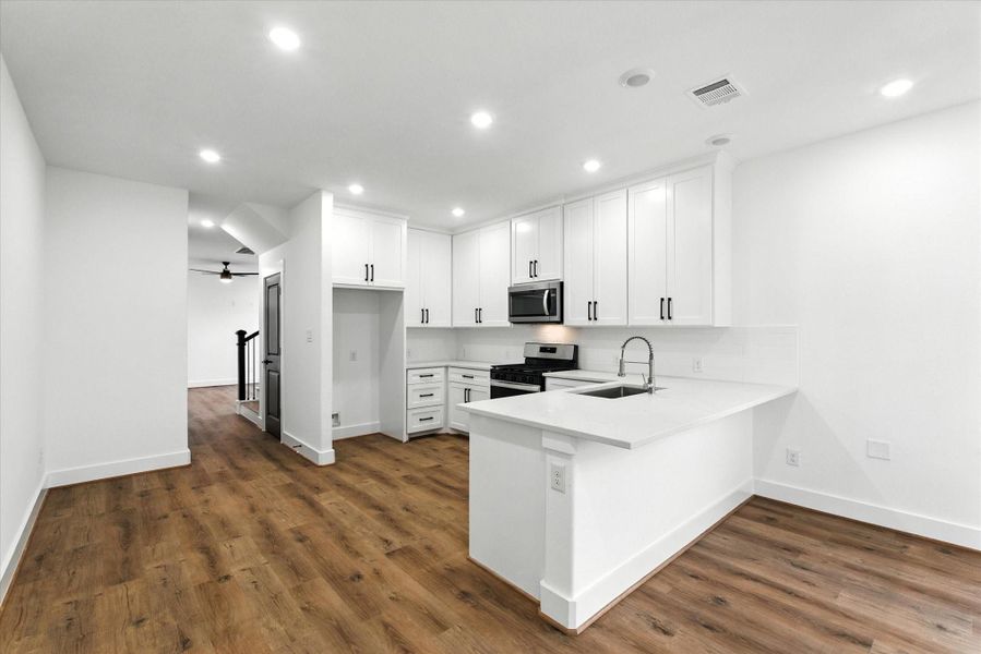 Discover a spacious walk-in pantry, floor-to-ceiling cabinets, a gas stove, and a built-in microwave—all beautifully showcased in your stunning black-and-white kitchen!