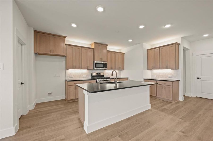This dream kitchen features beautiful cabinets that blend perfectly with the neutral flooring and gorgeous counter tops.