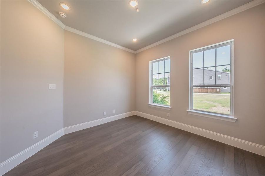 Room featuring two double-hung windows with grid patterns, recessed ceiling lighting, crown molding, baseboards, and wood-finish flooring