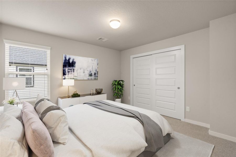 This bedroom features a neutral color palette with soft gray walls and carpet. It includes a large bed with stylish pillows, a window for natural light, a modern dresser, and a double-door closet. The room is accented with tasteful artwork and a cozy atmosphere.