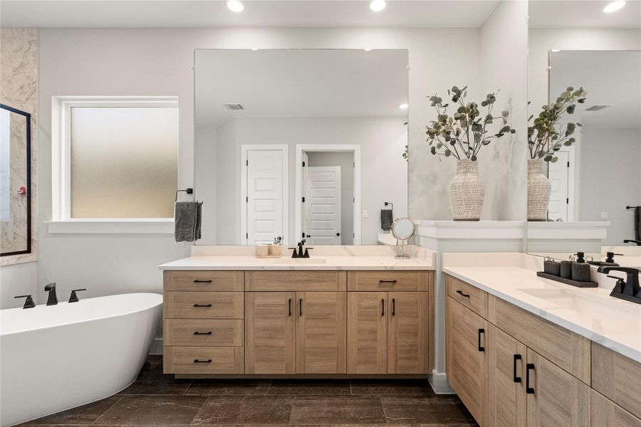 Luxurious primary bath showcasing a freestanding soaking tub and dual vanities with expansive mirrors. Luxurious primary bath showcasing a freestanding soaking tub and dual vanities with expansive mirrors.